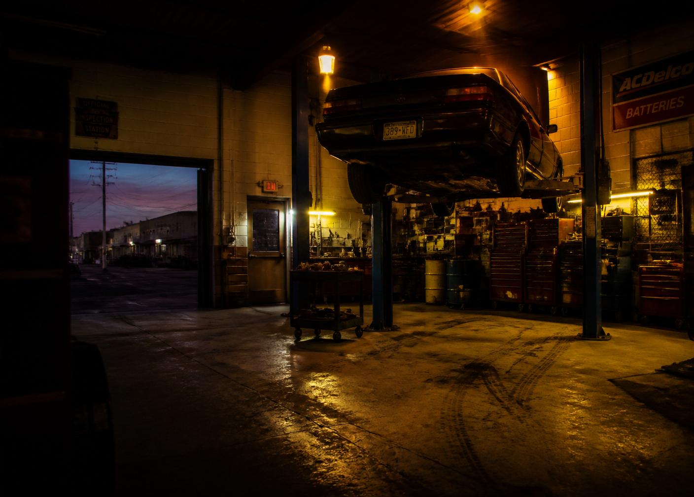 Interior of the A&J garage at dusk with a car on the lift